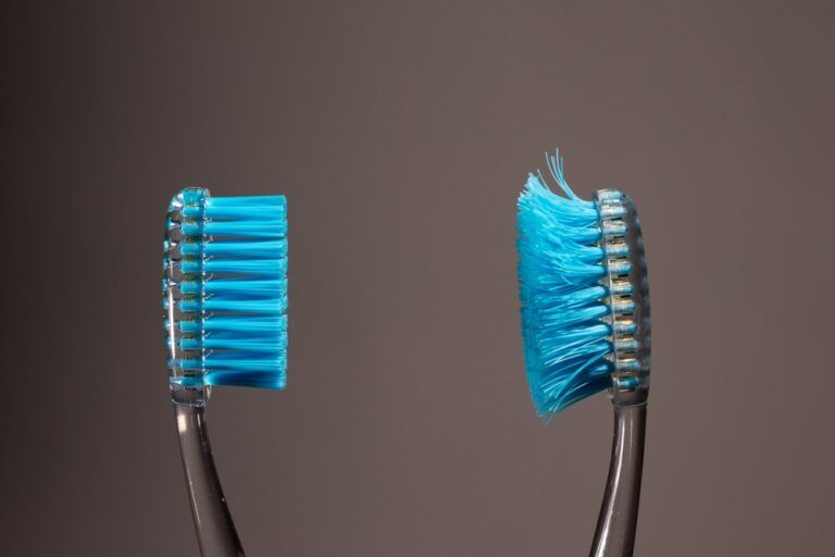 A new toothbrush with firm bristles stands next to an old, worn toothbrush